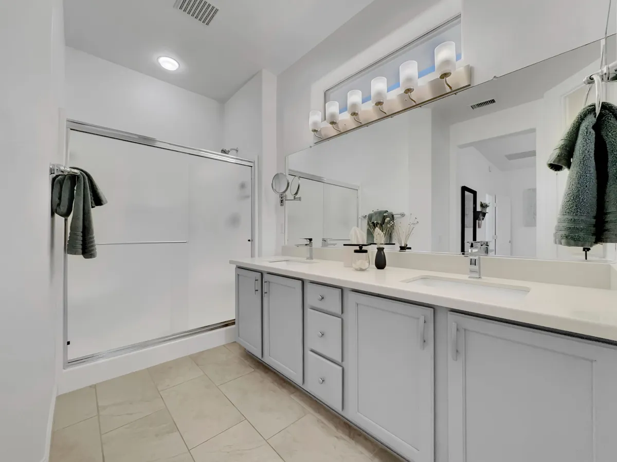 A modern bathroom featuring a vanity with sink, a separate shower area, bright light fixtures, and a mirror. The scene feels fresh and calming, ideal for self-care routines.