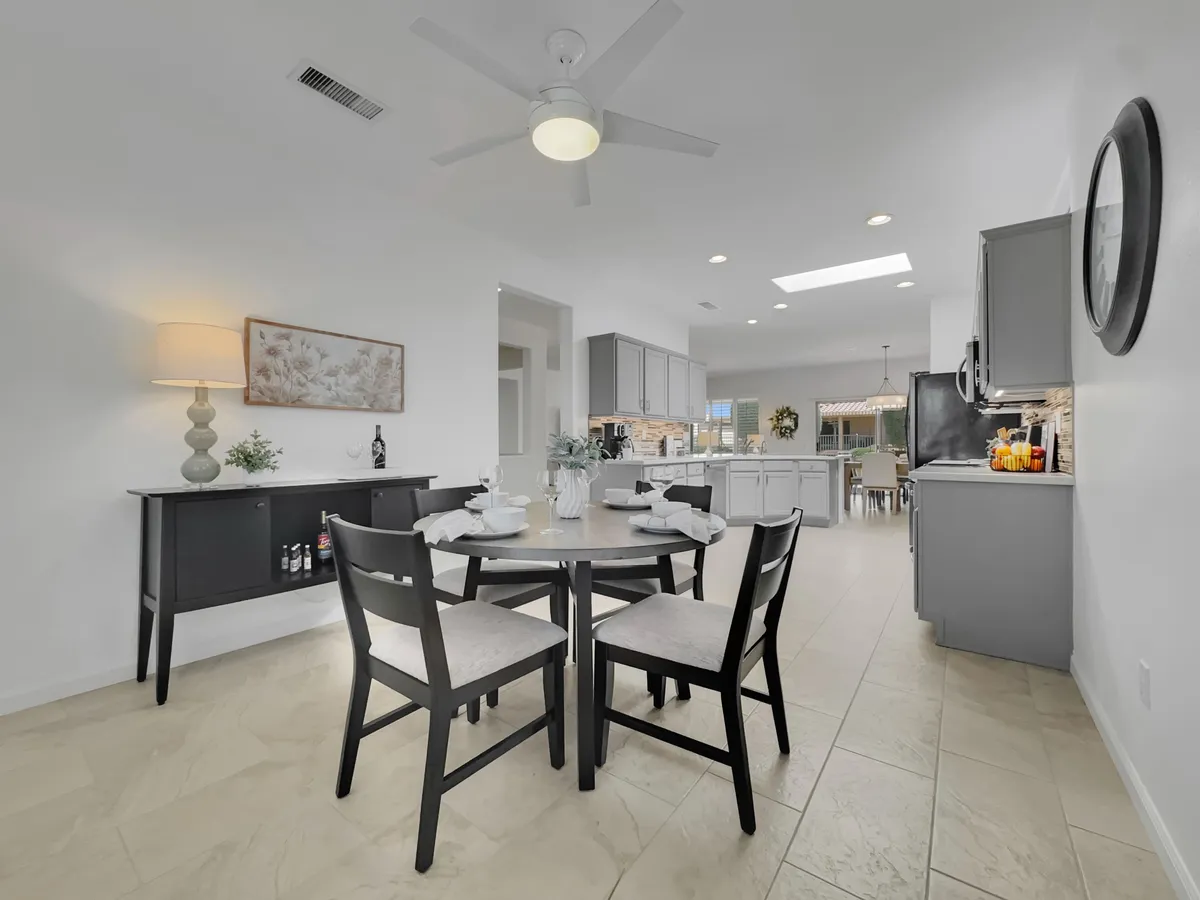 A dining area with a table beautifully set for a meal, the kitchen visible in the background, and tasteful decorative accents like a lamp and artwork on the wall. The scene radiates warmth and invites communal dining experiences.