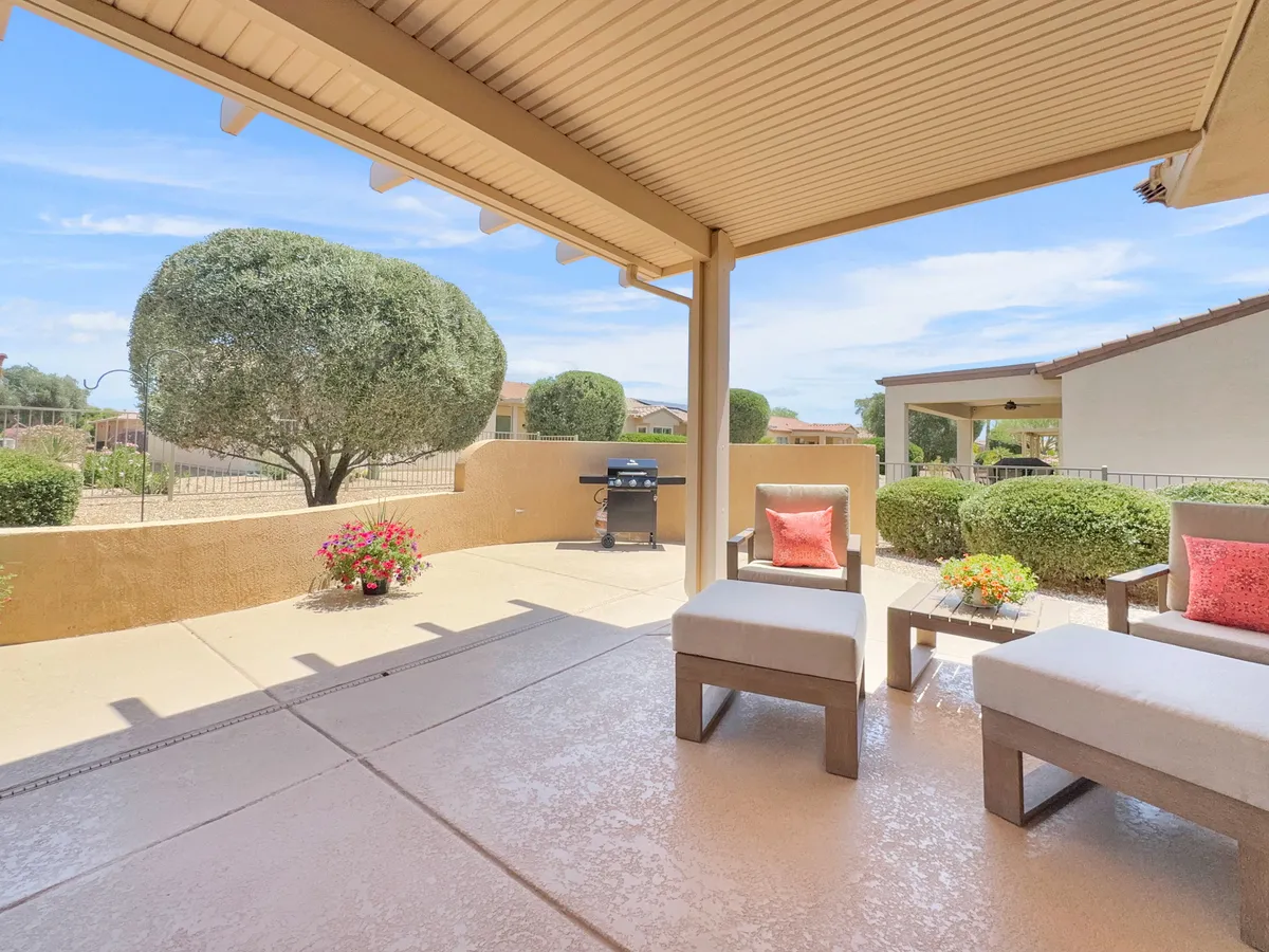 A cozy outdoor seating area with a grill and well-manicured greenery sets the scene for both casual relaxation and lively social gatherings. The arrangement is inviting and suggests a seamless blend of comfort and nature.
