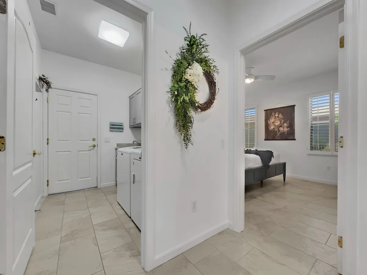 This image features a cozy and inviting entryway, complete with a decorative wreath on the wall, a doorway leading into the bedroom, and a glimpse of the laundry area. The space exudes a welcoming atmosphere, suggesting a warm arrival point for guests and residents alike.